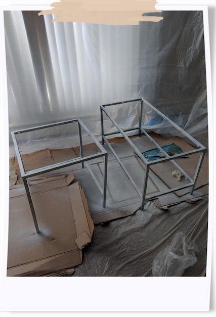 Started of priming indoors. Word of advice, no matter how well-well-ventilted your home is, DO NOT prime indoors. Two primed tables spray painted indoors of living room that has been covered in plastic sheets