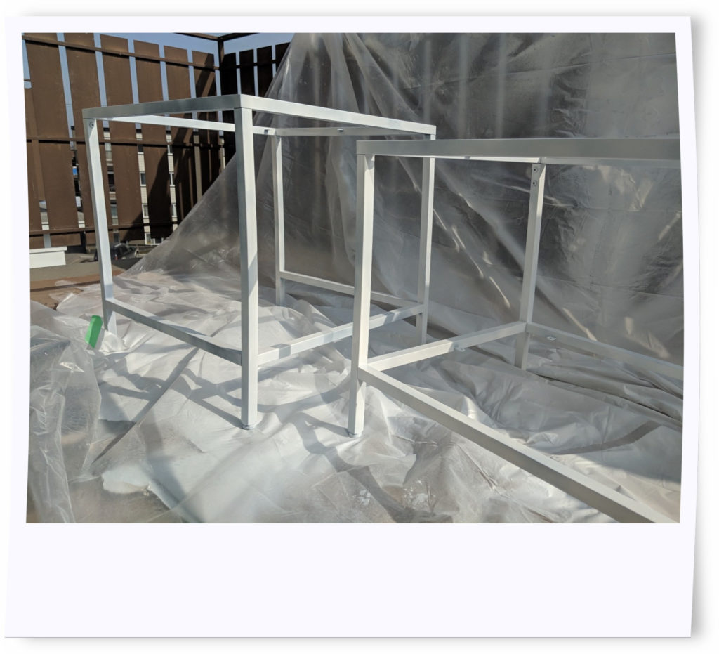 Vittsjo nesting tables moved outdoors on balcony covered in plastic sheets to complete priming process.