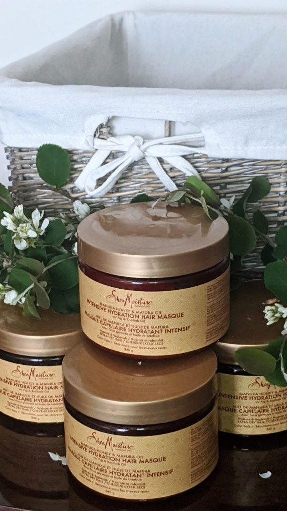 SheaMoisture Manuka Honey and Mafura Oil Intensive Hydration Hair Masque displayed on table with branch and basket behind for aesthetic purpose 