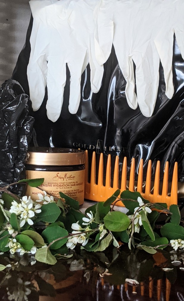 SheaMoisture Manuka Honey and Mafura Oil Intensive Hydration Hair Masque. Application setup laid out on table; wide tooth comb, latex glove, SheaMoisture Manuka Honey and Mafura Oil Hydration  Hair Masque ,  plastic cap, heating cap, branch for aesthetic