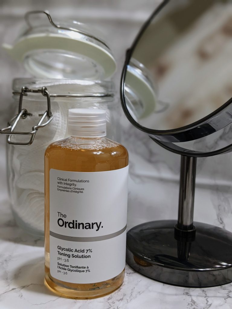Sephora online purchase of The Ordinary's Glycolic Acid &% Toning Solution, retailed for $8.70 CAD , Size: 8oz, on marbled vanity counter with mirror and jar of cotton pads in the background for decoration