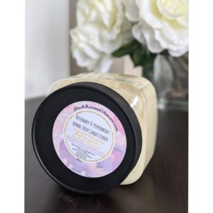 BlackHairandSkincare Rosemary and Peppermint Herbal Deep Conditioner ft. Sydney Nicole Products displaying label on the lid, on wooden table, flower in the background
