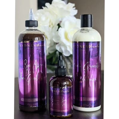 BlackHairandSkincare ft. Sydney Nicole Products Trio Set which includes: The Hair Growth Conditioner, Raw African Black Soap Hair Growth Shampoo, and the Organic Hair Growth Oil on wooden table with white flower in the background
